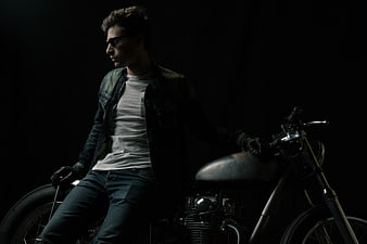 Man in Sunglasses Sitting on Vintage Motorcycle in Dark Studio