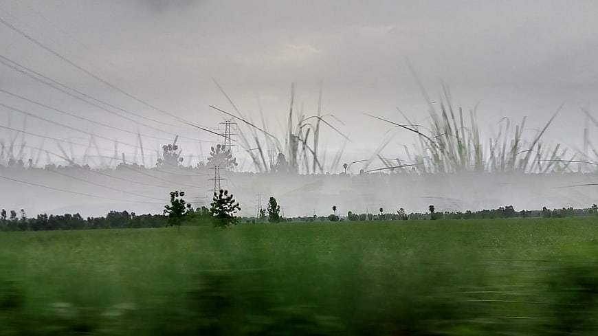 Motion blur view of green fields and power lines from moving vehicle