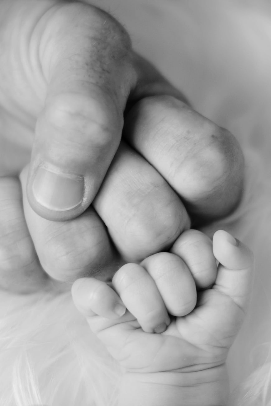 Black and white close-up of father holding baby hand