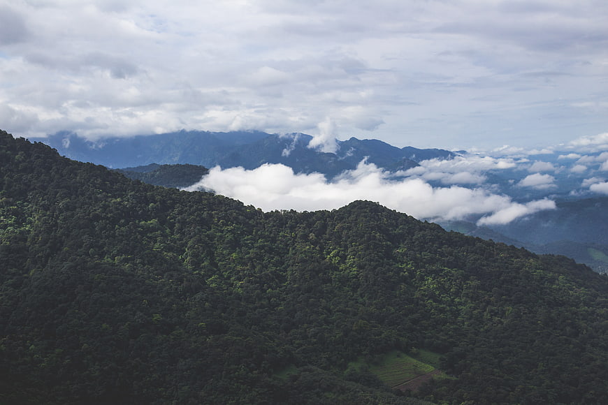 Lush Green Mountain Range with Clouds and Mist