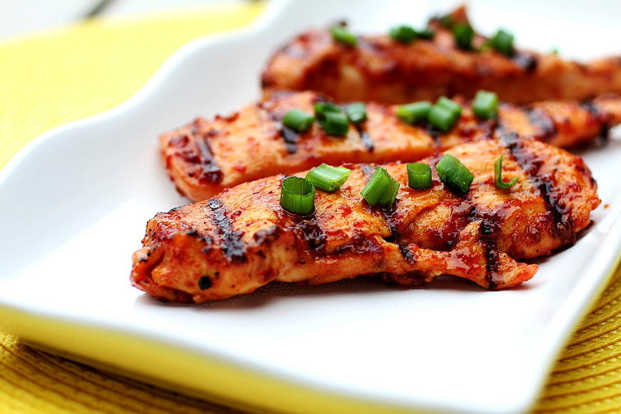 Grilled Spicy Chicken Strips with Green Onions on White Plate