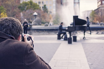 Photographer capturing pianist playing grand piano in city park