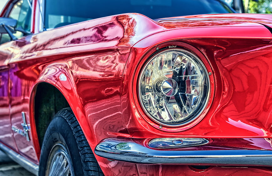 Close-up of Classic Red Ford Mustang Headlight and Chrome Bumper