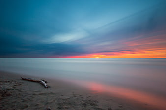 Serene Long Exposure Sunset Seascape with Driftwood
