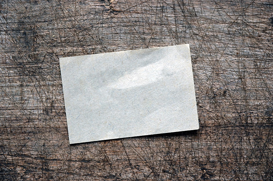 Blank gray paper note on scratched rustic wooden table surface
