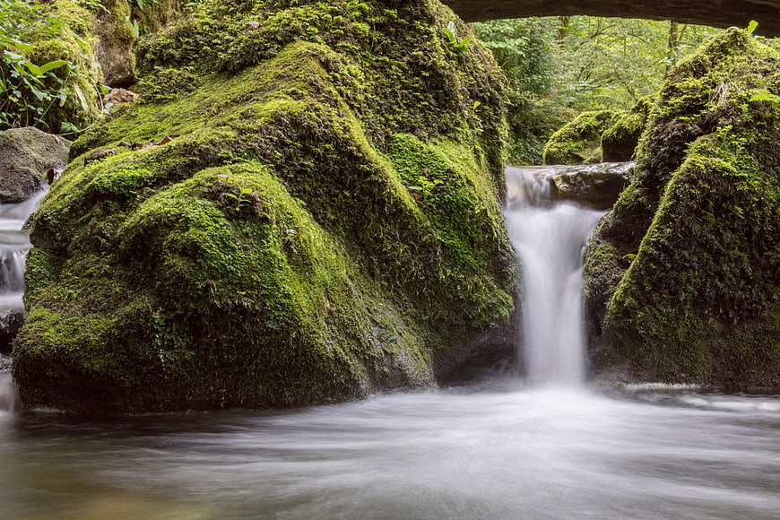Mossy waterfall in lush green forest with silky water flow