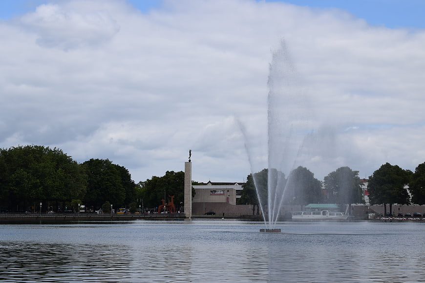 Water fountain spraying in lake with city skyline and monument