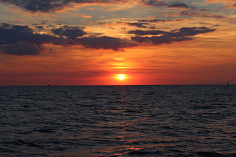 Vibrant Orange Sunset Over Baltic Sea with Sailboats
