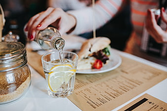 Woman pouring water with lemon into a glass at a cafe