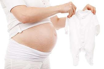 Pregnant woman holding white baby bodysuit on white background