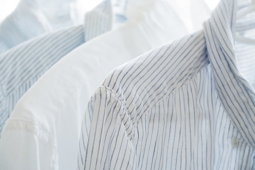 Close-up of striped and white shirts hanging on a rack