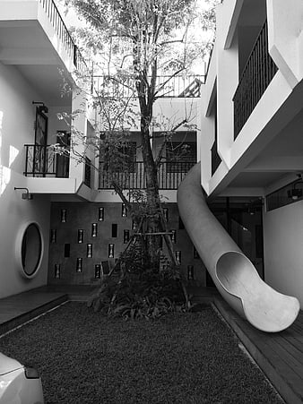 Black and white modern hotel courtyard with slide and tree