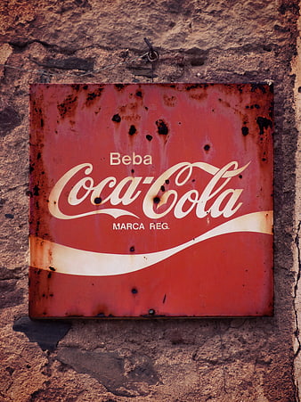 Vintage Rusty Coca-Cola Sign on Textured Stone Wall