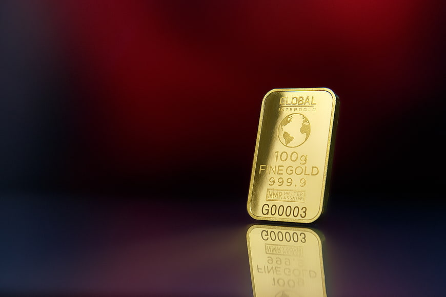 100g Gold Bar on Reflective Surface with Red Background