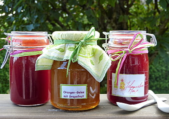 Homemade fruit jelly jars with decorative ribbons on a wooden table