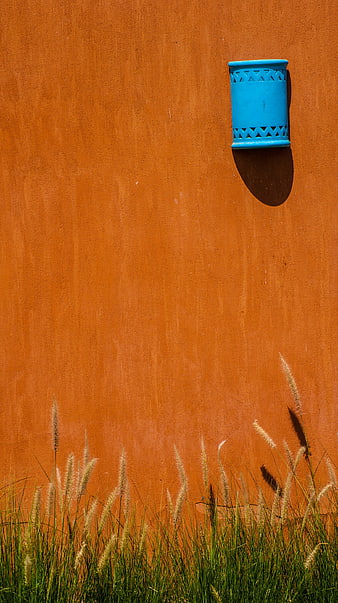 Blue decorative lamp on orange textured wall with grass