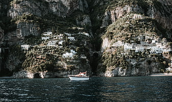White boat anchored in front of cliffside village