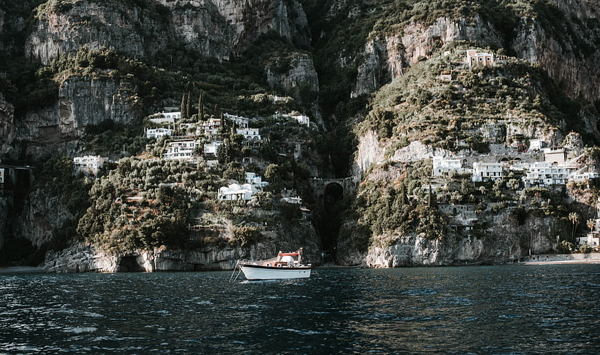 White boat anchored in front of cliffside village