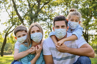 Family wearing face masks outdoors in a park