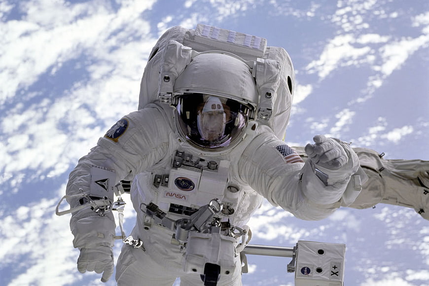 Astronaut in Space Suit Floating Above Earth Clouds