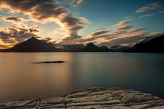 Serene Mountain Lake Sunset with Smooth Water and Rocky Foreground