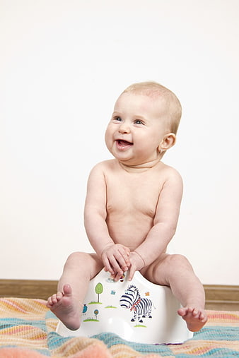 Happy baby girl sitting on potty training toilet