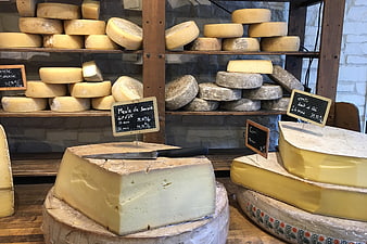 Artisanal cheese wheels displayed on wooden shelves in a shop