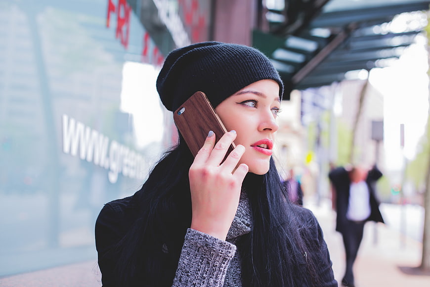 Woman in Beanie Talking on Smartphone on City Street