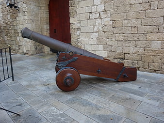 Historic cannon on wooden carriage against stone wall