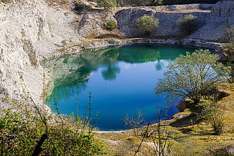 Turquoise quarry lake surrounded by white limestone cliffs