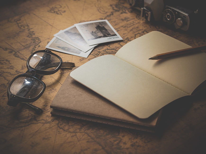 Vintage travel planning setup with map, notebook, and camera