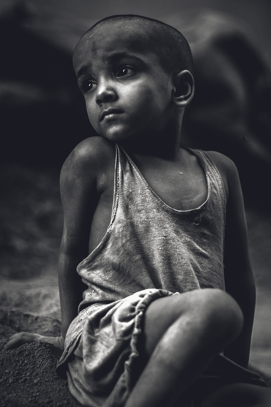 Black and white portrait of a young boy sitting outdoors