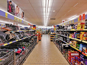Wide aisle in a well-stocked supermarket with shelves of products