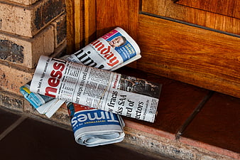 Rolled newspapers leaning against weathered brick wall and wooden door