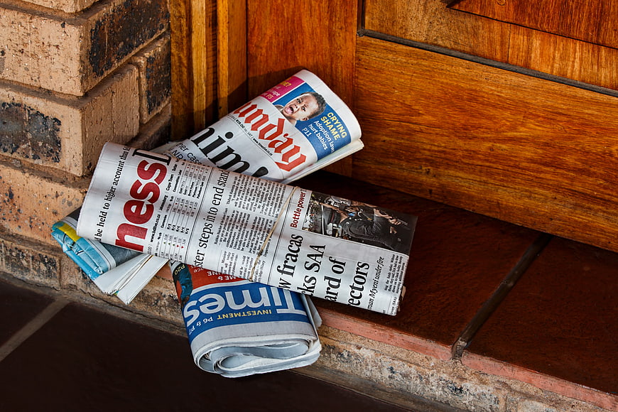 Rolled newspapers leaning against weathered brick wall and wooden door