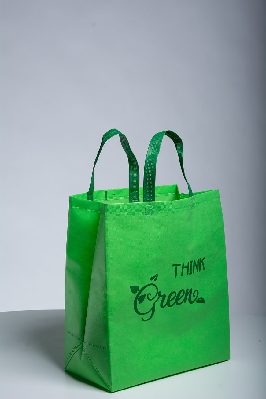 Green non-woven tote bag with Think Green slogan on grey background