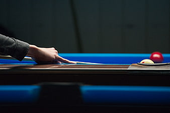 Close-up of hand aiming pool cue on billiard table