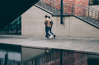 Two Men Walking Past Modern Architecture with Water Reflection