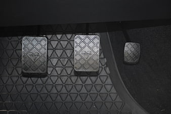 Close-up of three car pedals on a textured rubber floor mat