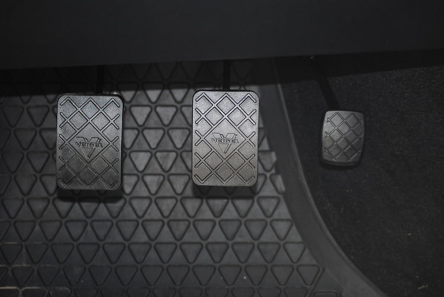 Close-up of three car pedals on a textured rubber floor mat