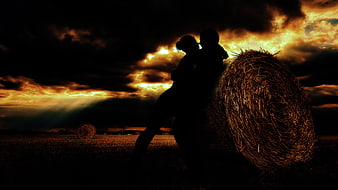 Silhouette of Mother and Child on Hay Bale at Sunset