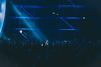 Silhouetted crowd at a concert with blue stage lights