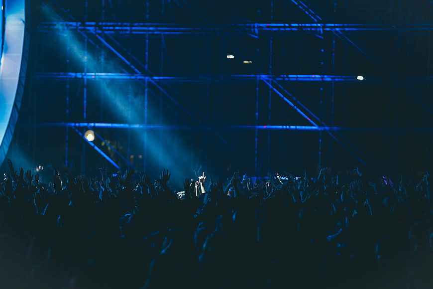 Silhouetted crowd at a concert with blue stage lights