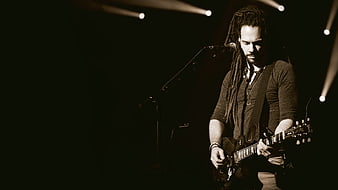 Male guitarist with dreadlocks performing on stage with spotlight