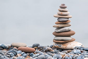 Balanced Stone Cairn on Pebble Beach with Misty Background
