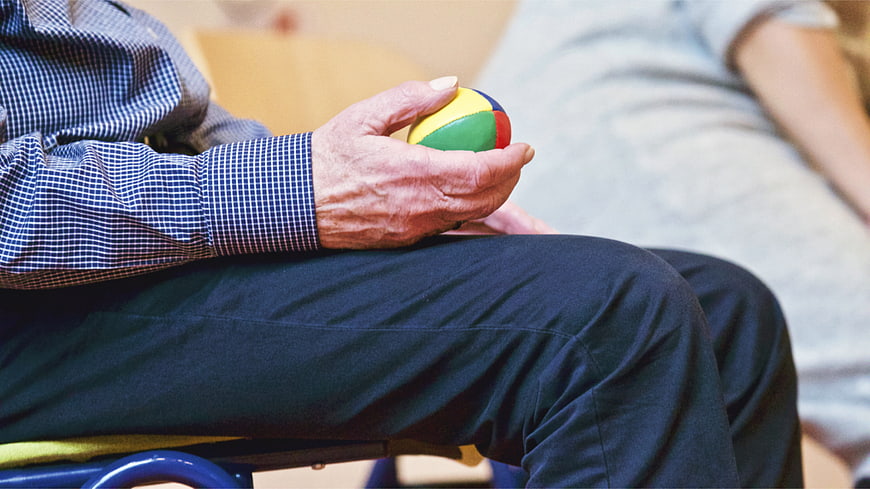 Senior man holding colorful therapy ball in hand