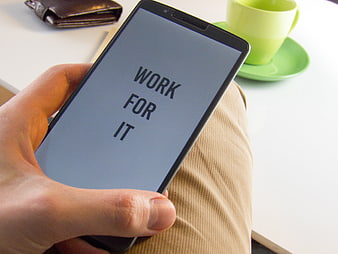 Hand holding smartphone with motivational text work for it