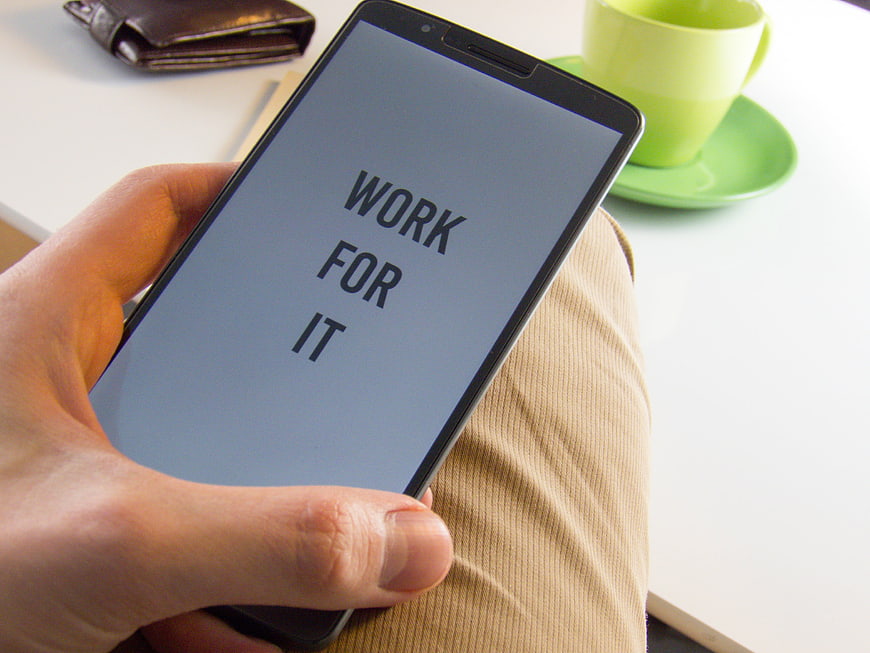 Hand holding smartphone with motivational text work for it
