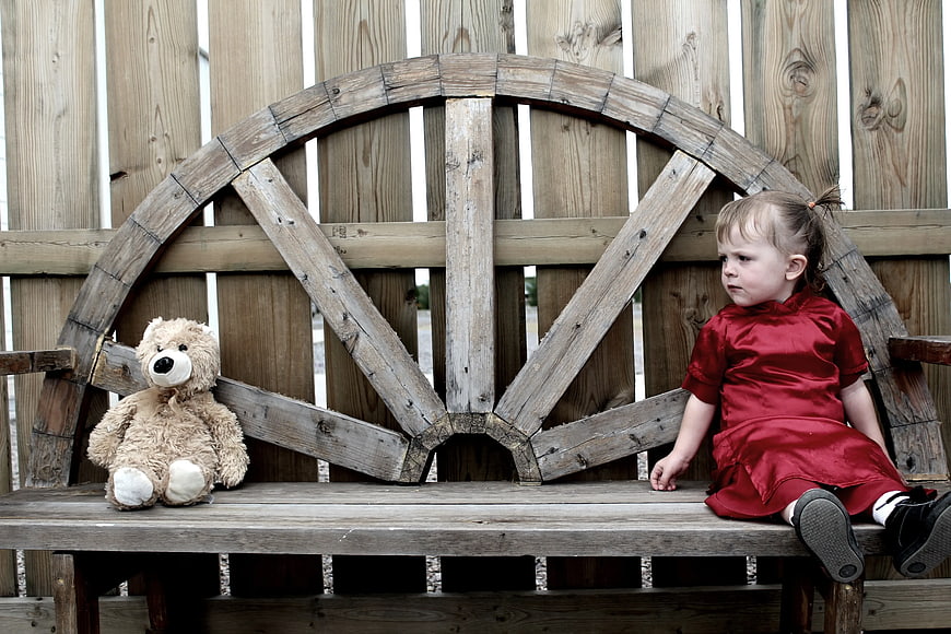 Toddler Girl in Red Dress Sitting on Wooden Bench with Teddy Bear