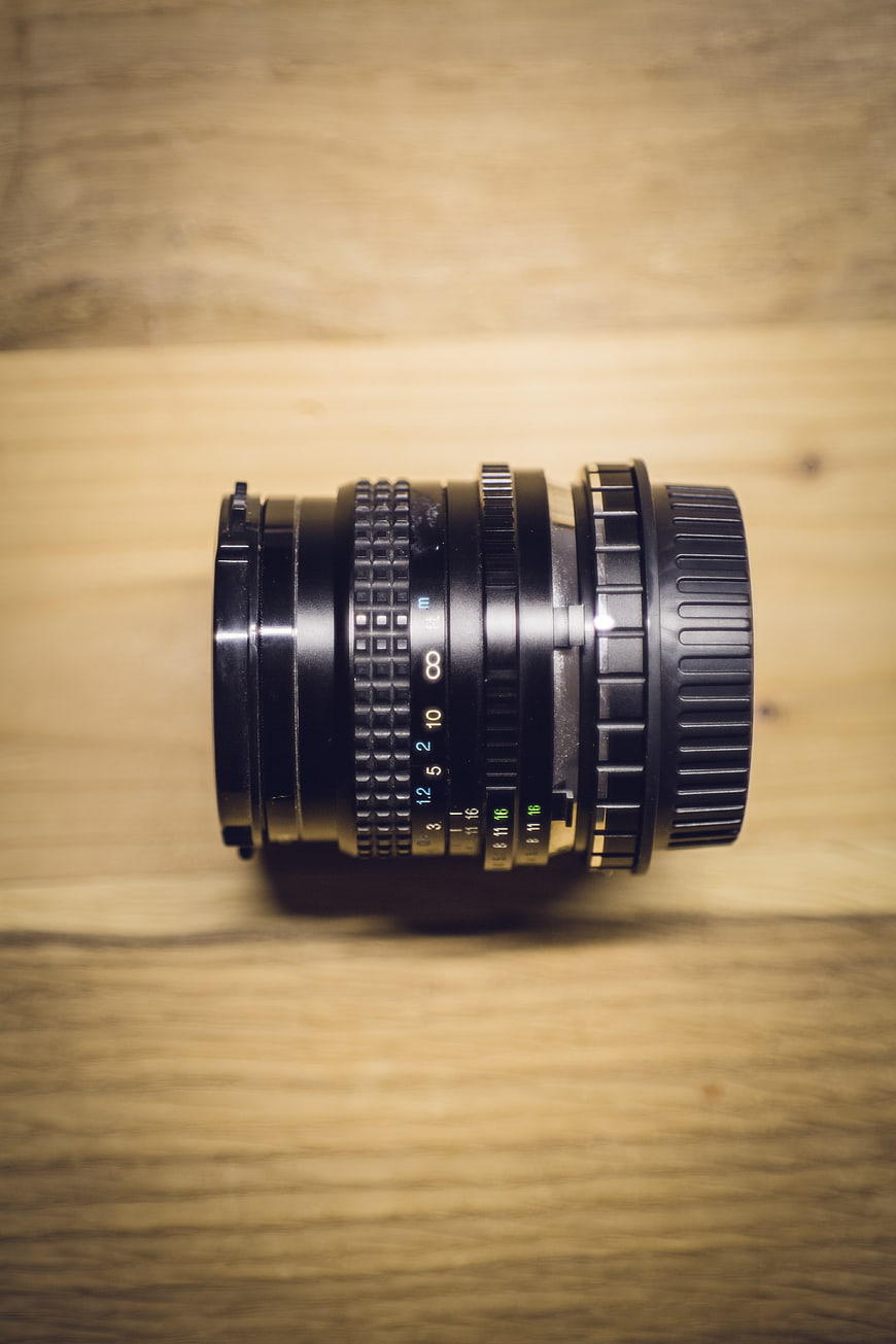 Vintage black camera lens on wooden table background